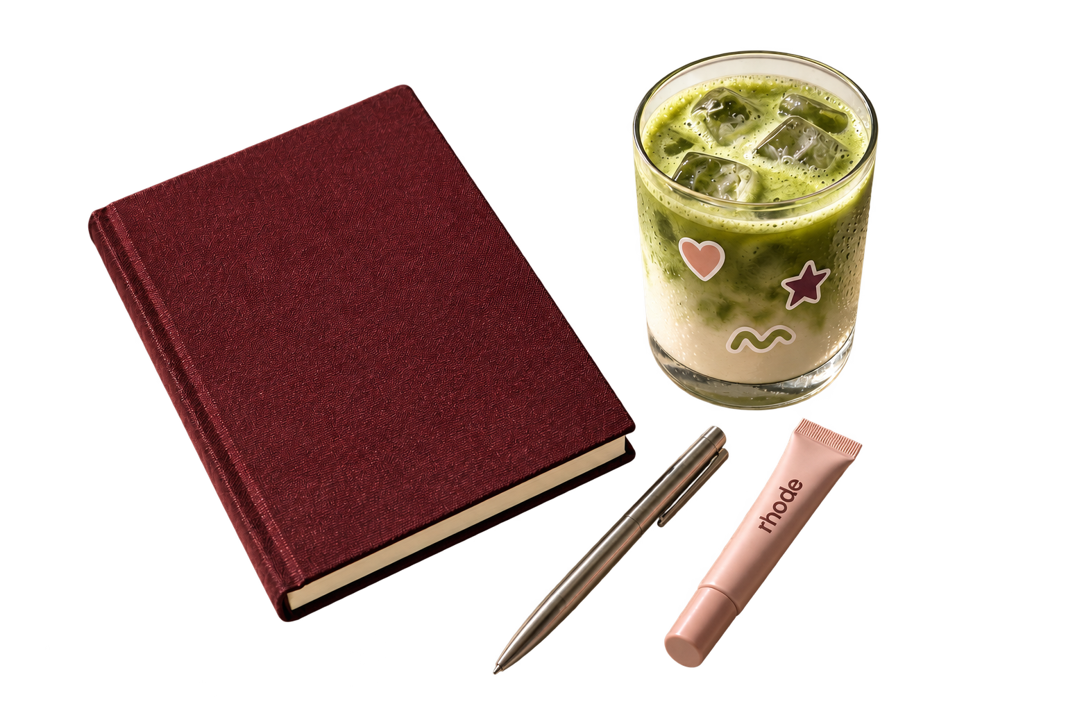 Objetos de inspiración, composición generada con IA: cuaderno burgundy, iced matcha con stickers, pluma plateada y labial rosa de rhode.